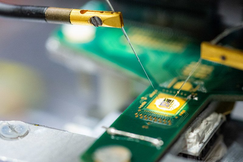Chip ottico-integrato collegato alla scheda elettronica di controllo con tecnica di wire bonding e accoppiato con due fibre ottiche per lelaborazione di segnali per telecomunicazioni alle lunghezze donda infrarosse.