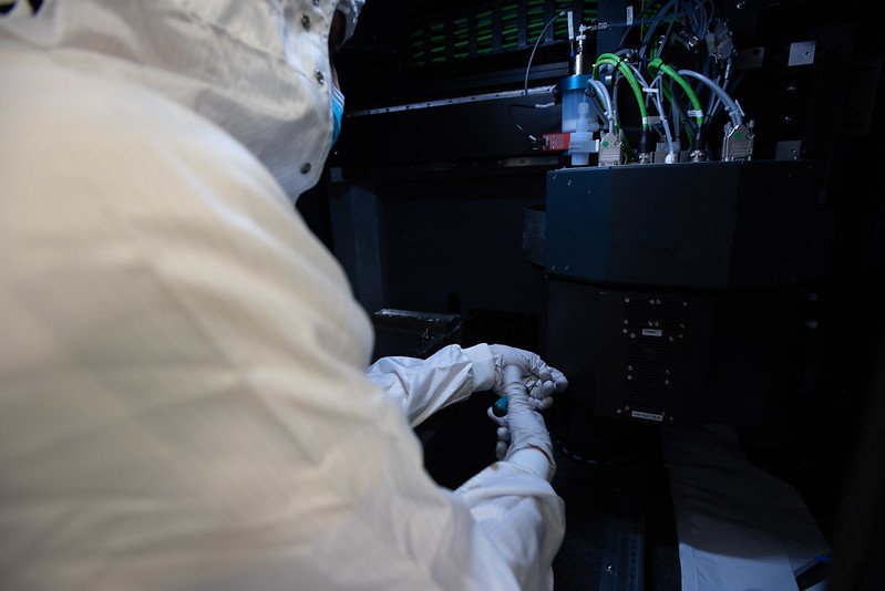A PhD candidate is working with a inkjet-aerosol jet printer installed in the clean room of Polifab. A PhD candidate is working with a inkjet-aerosol jet printer installed in the clean room of Polifab.