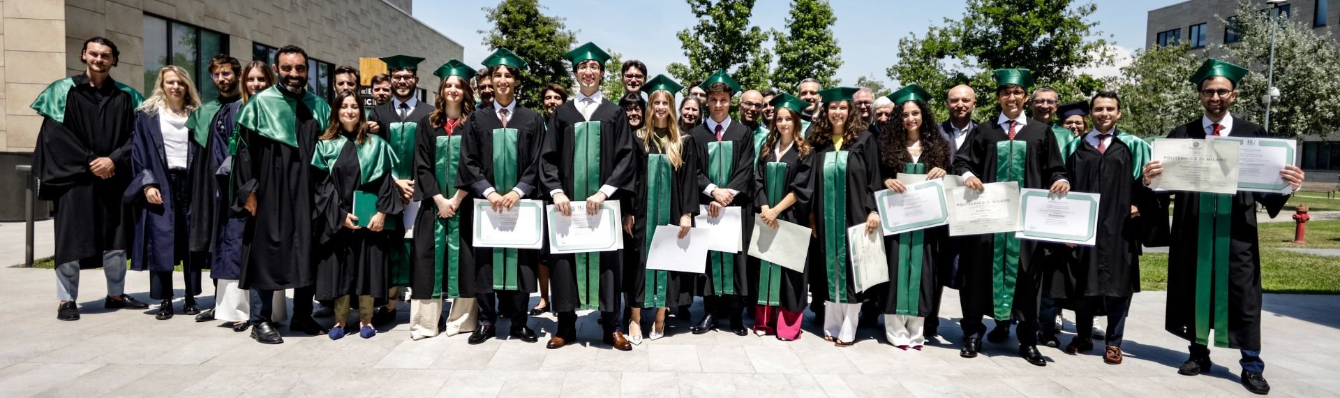 A group of graduates poses for a photo in front of a building. A group of graduates poses for a photo in front of a building.