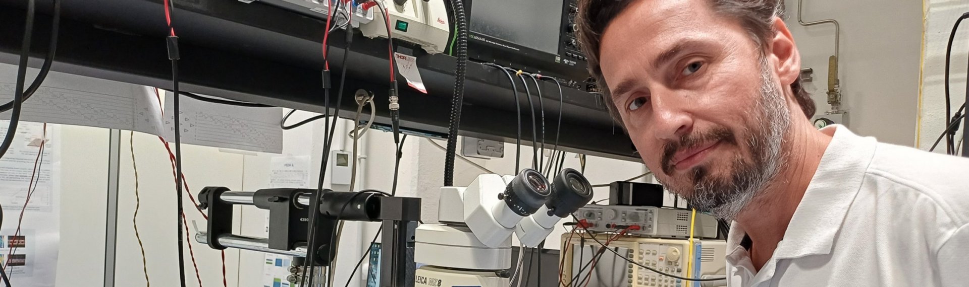 Un uomo con barba e camicia bianca è in piedi davanti a un computer.