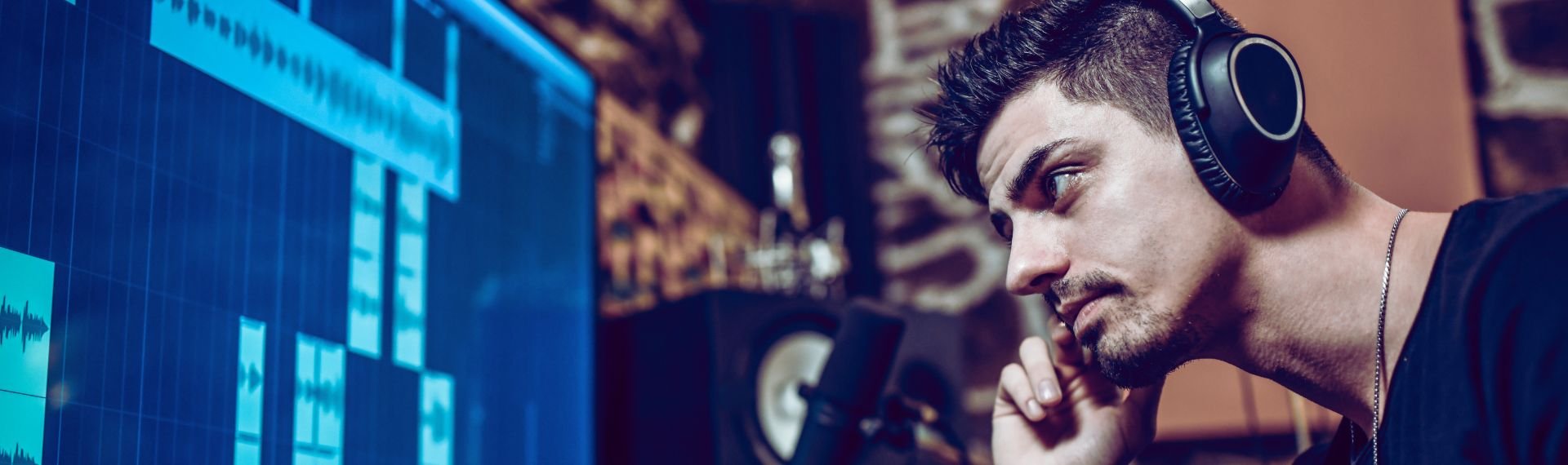 Uomo con cuffie davanti a uno schermo di computer, concentrato su un'attività digitale.