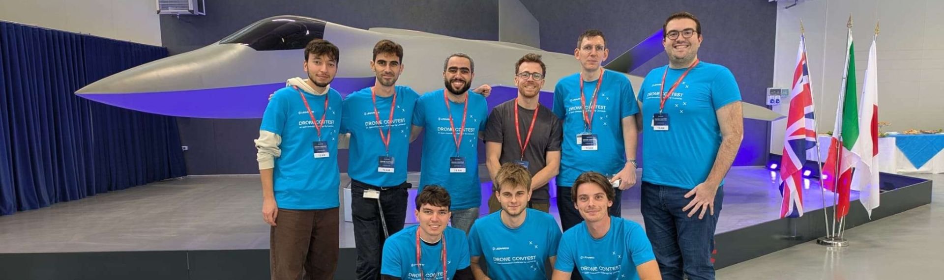 Un gruppo di persone in magliette blu posa con un drone.